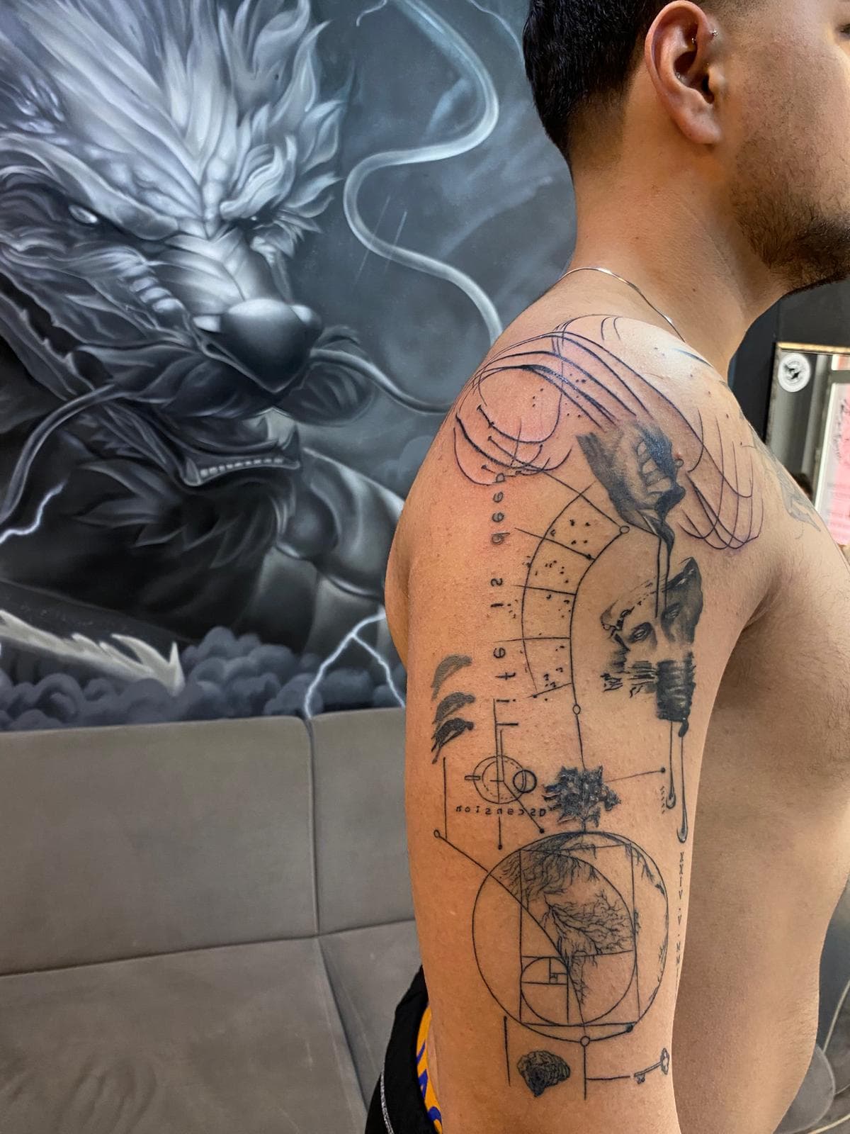 Üst kolda ince çizgi kutsal geometri kompozisyonu: Fibonacci sarmalı, heykel portresi ve yazı — Ersin Tattoo Bakırköy